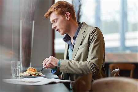 side view of someone sitting in chair - Man sitting in a restaurant taking lunch Stock Photo - Premium Royalty-Free, Code: 6108-06166041