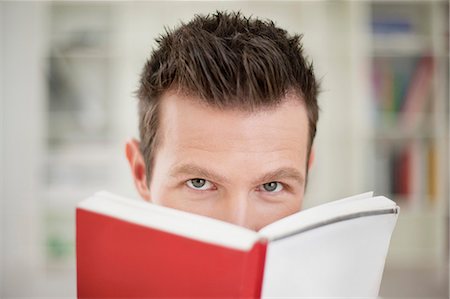 Portrait of a man holding a book in front of his face Stock Photo - Premium Royalty-Free, Code: 6108-06166020