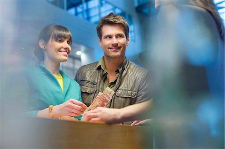 paying with cash - Happy couple standing at a bank counter Stock Photo - Premium Royalty-Free, Code: 6108-06166030