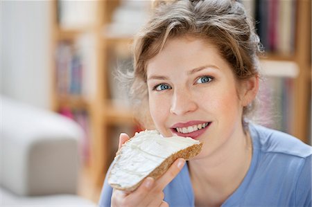 Portrait of a woman eating toast with cream spread on it Fotografie stock - Premium Royalty-Free, Codice: 6108-06166243