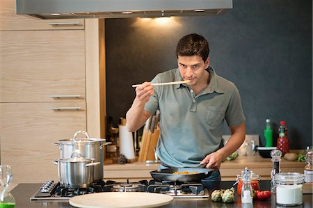 simsearch:6108-06166653,k - Man tasting food in the kitchen Foto de stock - Royalty Free Premium, Número: 6108-06166279