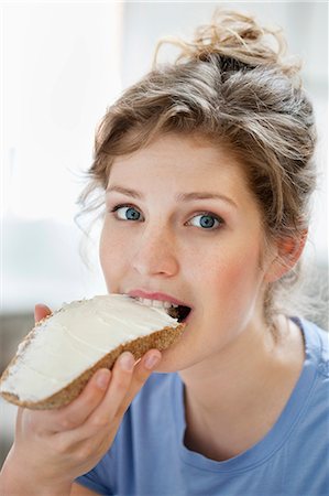 people eating cheese - Portrait of a woman eating toast with cream spread on it Stock Photo - Premium Royalty-Free, Code: 6108-06166212