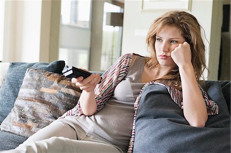 Woman watching television and looking serious Stock Photo - Premium Royalty-Free, Code: 6108-06166239