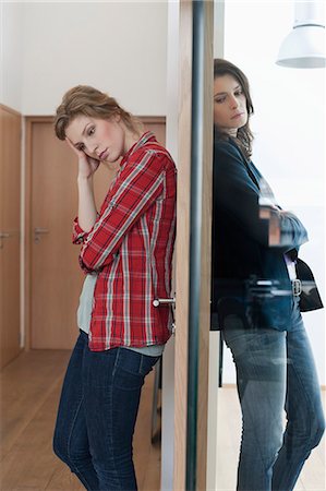 Two female friends standing back to back against a door Stock Photo - Premium Royalty-Free, Code: 6108-06166359