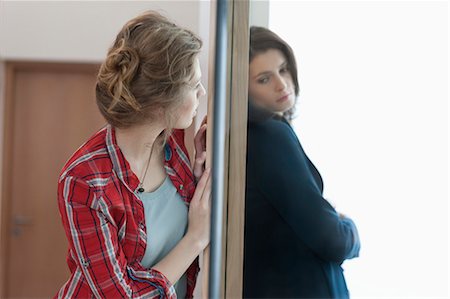 relationship problem - Two female friends standing back to back against a door Stock Photo - Premium Royalty-Free, Code: 6108-06166362