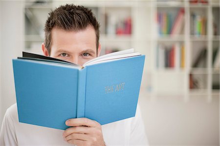 picture of a man peeking - Portrait of a holding a book in front of his face Stock Photo - Premium Royalty-Free, Code: 6108-06166300