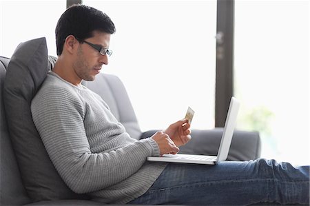 shopping laptop eyeglasses - Man holding a credit card and using a laptop Stock Photo - Premium Royalty-Free, Code: 6108-06166314