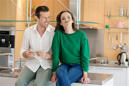 Couple playing with green bean in the kitchen Stock Photo - Premium Royalty-Free, Code: 6108-06166403