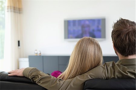 sitting on backside sofa - Rear view of a couple watching television Stock Photo - Premium Royalty-Free, Code: 6108-06166402