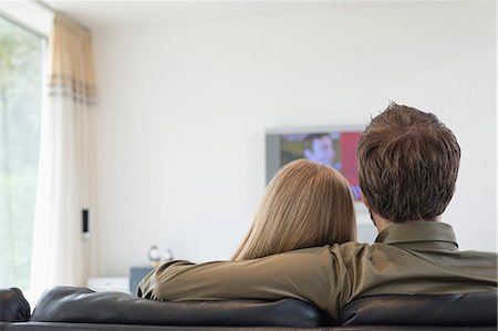 sitting on couch from back - Rear view of a couple watching television Stock Photo - Premium Royalty-Free, Code: 6108-06166415