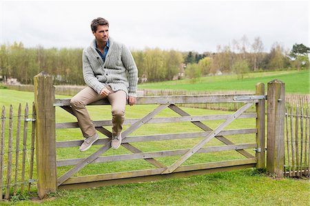 Man sitting on the gate of a cottage Stock Photo - Premium Royalty-Free, Code: 6108-06166542