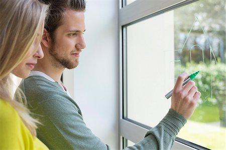 Woman looking at an architect drawing a design on the window glass Stock Photo - Premium Royalty-Free, Code: 6108-06166551