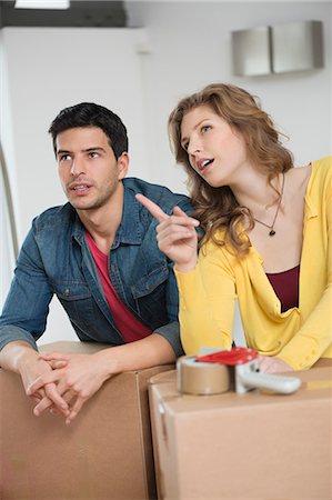 Couple leaning over cardboard boxes discussing Stock Photo - Premium Royalty-Free, Code: 6108-06166523