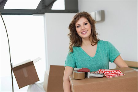 Woman carrying cardboard box and smiling Stock Photo - Premium Royalty-Free, Code: 6108-06166521