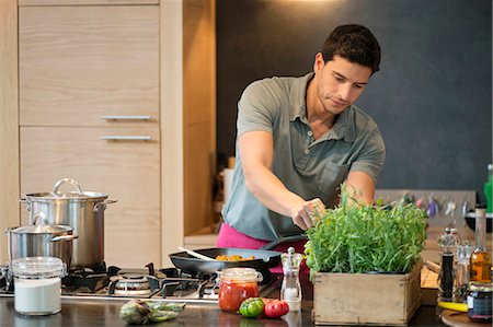 simsearch:6108-06166729,k - Man preparing food in the kitchen Foto de stock - Sin royalties Premium, Código: 6108-06166644