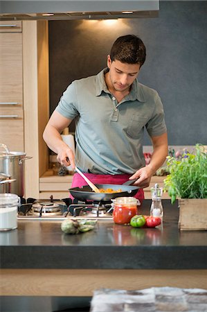 simsearch:6108-06166729,k - Man preparing food in the kitchen Foto de stock - Sin royalties Premium, Código: 6108-06166660