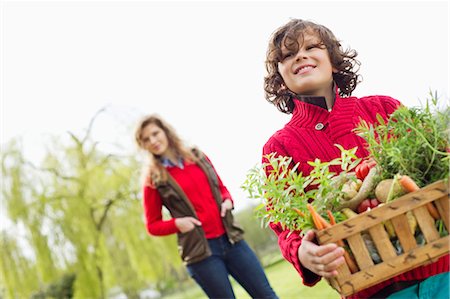 Boy holding a crate of assorted vegetables with his mother in a farm Stock Photo - Premium Royalty-Free, Code: 6108-06166681