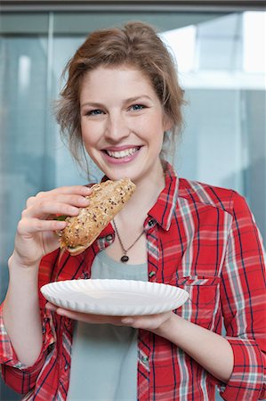 Portrait d'une femme mangeant sandwich et souriant Photographie de stock - Premium Libres de Droits, Code: 6108-06166698