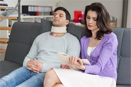 sick couple - Woman reading a book for her husband suffering from neckache Stock Photo - Premium Royalty-Free, Code: 6108-06166604