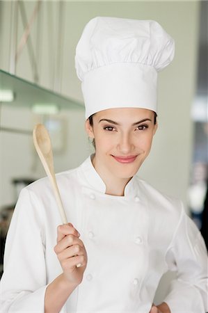 Happy female chef holding a wooden spoon Stock Photo - Premium Royalty-Free, Code: 6108-06166740
