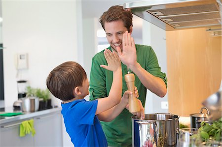 dad and kids cook - Man and son giving high five to each other in the kitchen Stock Photo - Premium Royalty-Free, Code: 6108-06166747