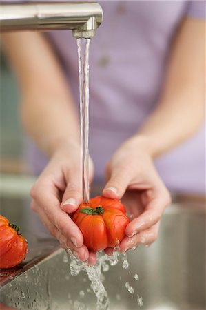 simsearch:6108-06166653,k - Woman washing tomatoes in the kitchen Foto de stock - Royalty Free Premium, Número: 6108-06166717