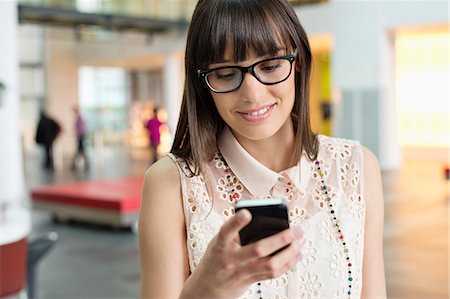 Businesswoman text messaging in an office Stock Photo - Premium Royalty-Free, Code: 6108-06166859