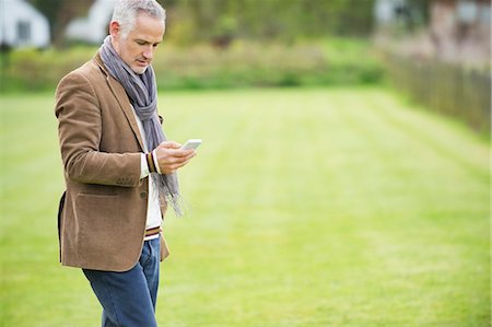 send message - Man text messaging on a mobile phone in a park Stock Photo - Premium Royalty-Free, Code: 6108-06166896