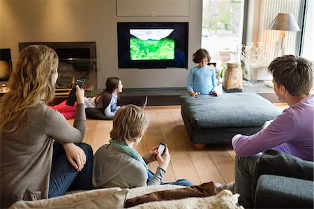 remote control tv - Family using electronic gadgets in a living room Stock Photo - Premium Royalty-Free, Code: 6108-06166952