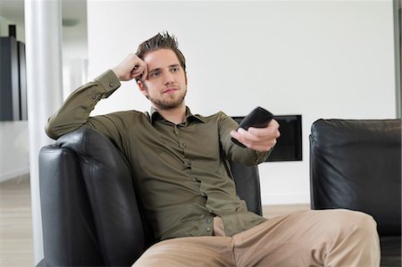 Man using remote control while watching television Foto de stock - Sin royalties Premium, Código: 6108-06166959
