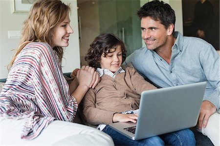 fraternité - Garçon avec ses parents à la maison à l'aide d'un ordinateur portable Photographie de stock - Premium Libres de Droits, Code: 6108-06166972