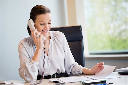 Businesswoman talking on a landline phone in an office Stock Photo - Premium Royalty-Free, Code: 6108-06166900
