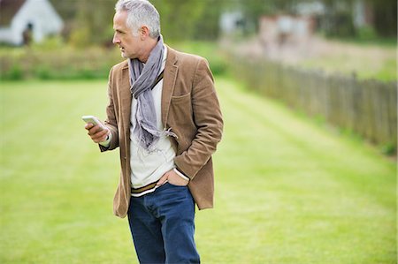 Man text messaging on a mobile phone in a lawn Foto de stock - Sin royalties Premium, Código: 6108-06166919