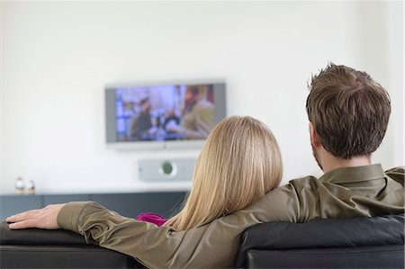 sitting on backside sofa - Rear view of a couple watching television Stock Photo - Premium Royalty-Free, Code: 6108-06166927