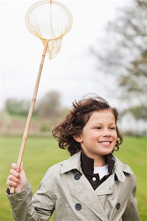 Boy running with a butterfly net in a park Stock Photo - Premium Royalty-Free, Code: 6108-06167040