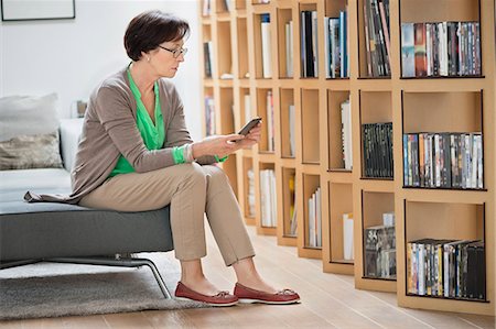 sitting on couch book - Woman sitting on a couch and reading a book Foto de stock - Sin royalties Premium, Código: 6108-06167067