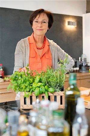 fashion for older women - Woman standing in the kitchen with an organic plant Stock Photo - Premium Royalty-Free, Code: 6108-06167093