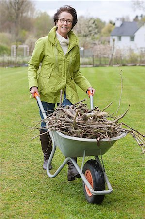 senior women gardening - Woman pushing a wheelbarrow full of branches Stock Photo - Premium Royalty-Free, Code: 6108-06167096