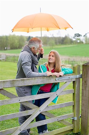 father and daughter talking - Man standing with his daughter in a farm with an umbrella Foto de stock - Sin royalties Premium, Código: 6108-06167195