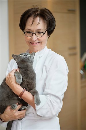 Woman holding a cat and smiling Stock Photo - Premium Royalty-Free, Code: 6108-06167103