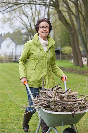 senior woman gardening - Woman pushing a wheelbarrow full of branches Stock Photo - Premium Royalty-Free, Code: 6108-06167119