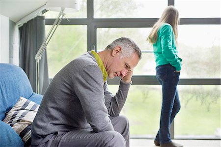 relationship problem - Man looking upset with his daughter standing in the background Stock Photo - Premium Royalty-Free, Code: 6108-06167248