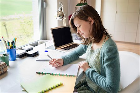 person sitting in chairs at desk side view - Girl studying at home Stock Photo - Premium Royalty-Free, Code: 6108-06167287