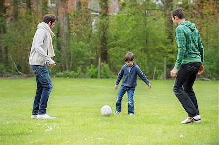 dads playing sports with kids - Boy playing soccer with two men in a park Stock Photo - Premium Royalty-Free, Code: 6108-06167353