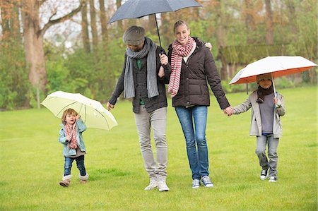 rain images for kids - Family walking with umbrellas in a park Stock Photo - Premium Royalty-Free, Code: 6108-06167376