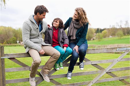 family, fence - Boy sitting with his parents on the gate of a cottage Stock Photo - Premium Royalty-Free, Code: 6108-06167385