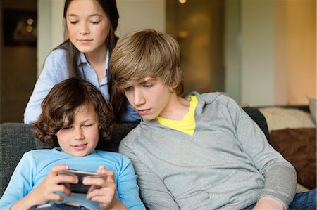 simsearch:6108-06905204,k - Boy using a cellphone with his brother and sister at home Stock Photo - Premium Royalty-Free, Code: 6108-06167300