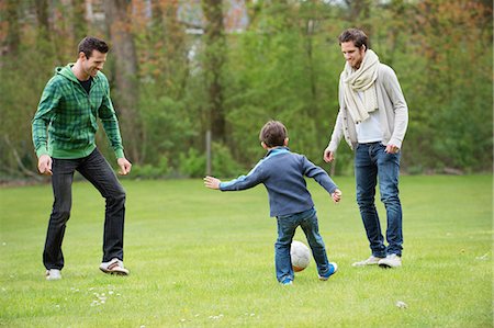 Garçon jouant au soccer avec deux hommes dans un parc Photographie de stock - Premium Libres de Droits, Code: 6108-06167323