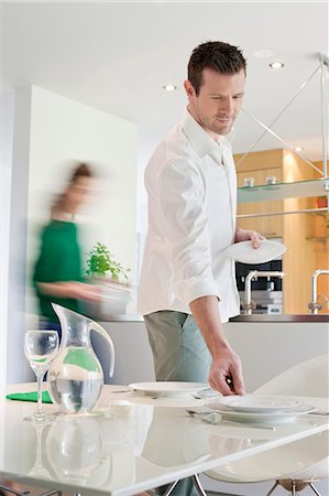 dining table plates dinner - Couple preparing to serve dinner Stock Photo - Premium Royalty-Free, Code: 6108-06167456