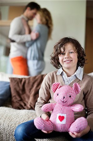 Boy sitting with a toy with his parents romancing in the background Foto de stock - Sin royalties Premium, Código: 6108-06167499